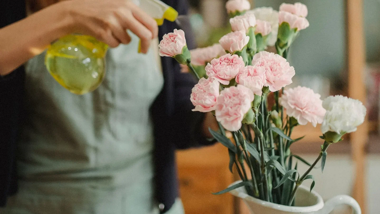 Fleuriste qui vaporise de l’eau sur un bouquet dans un vase