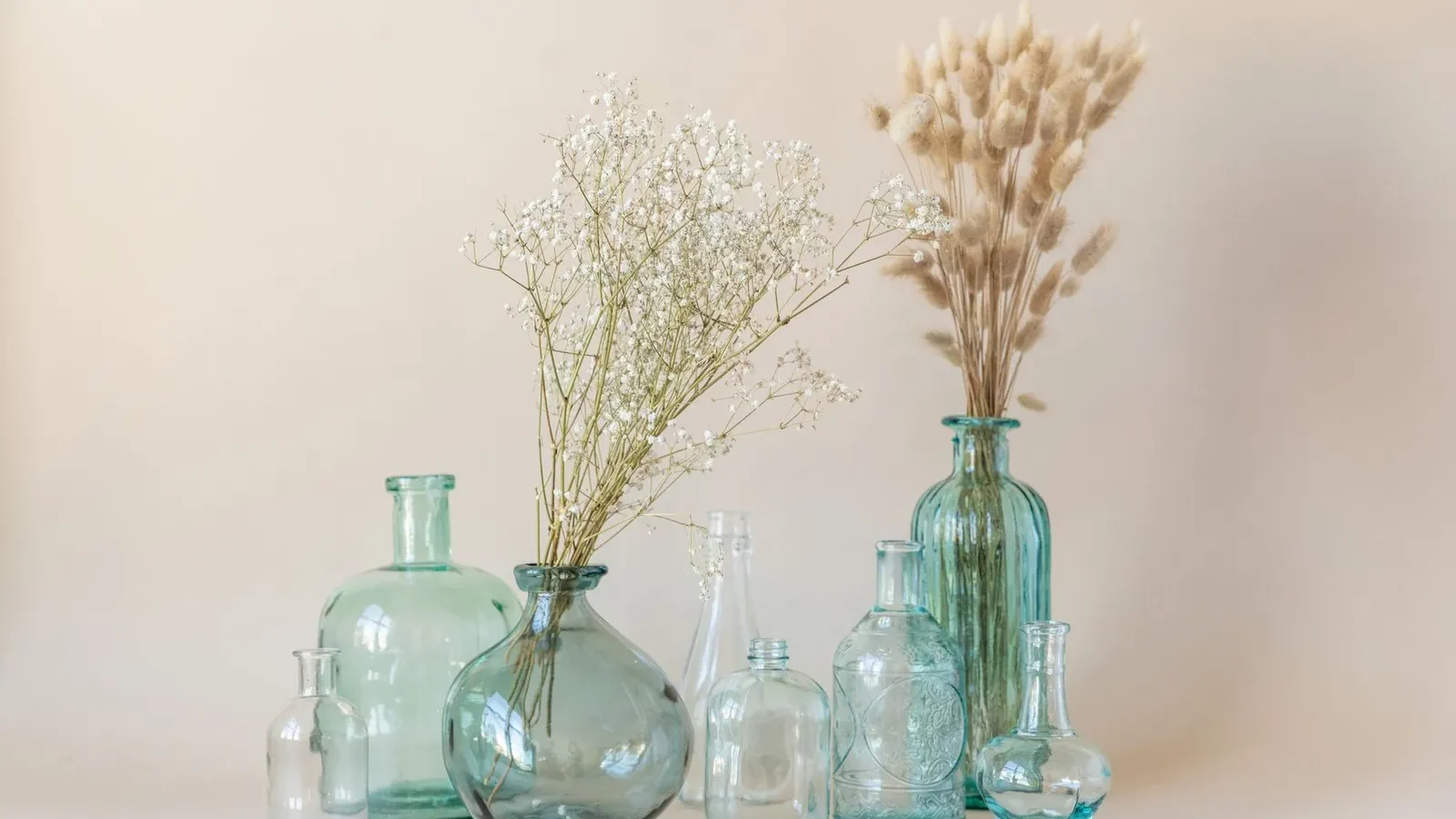 Vases en verre clair et bleu garnis de fleurs séchées