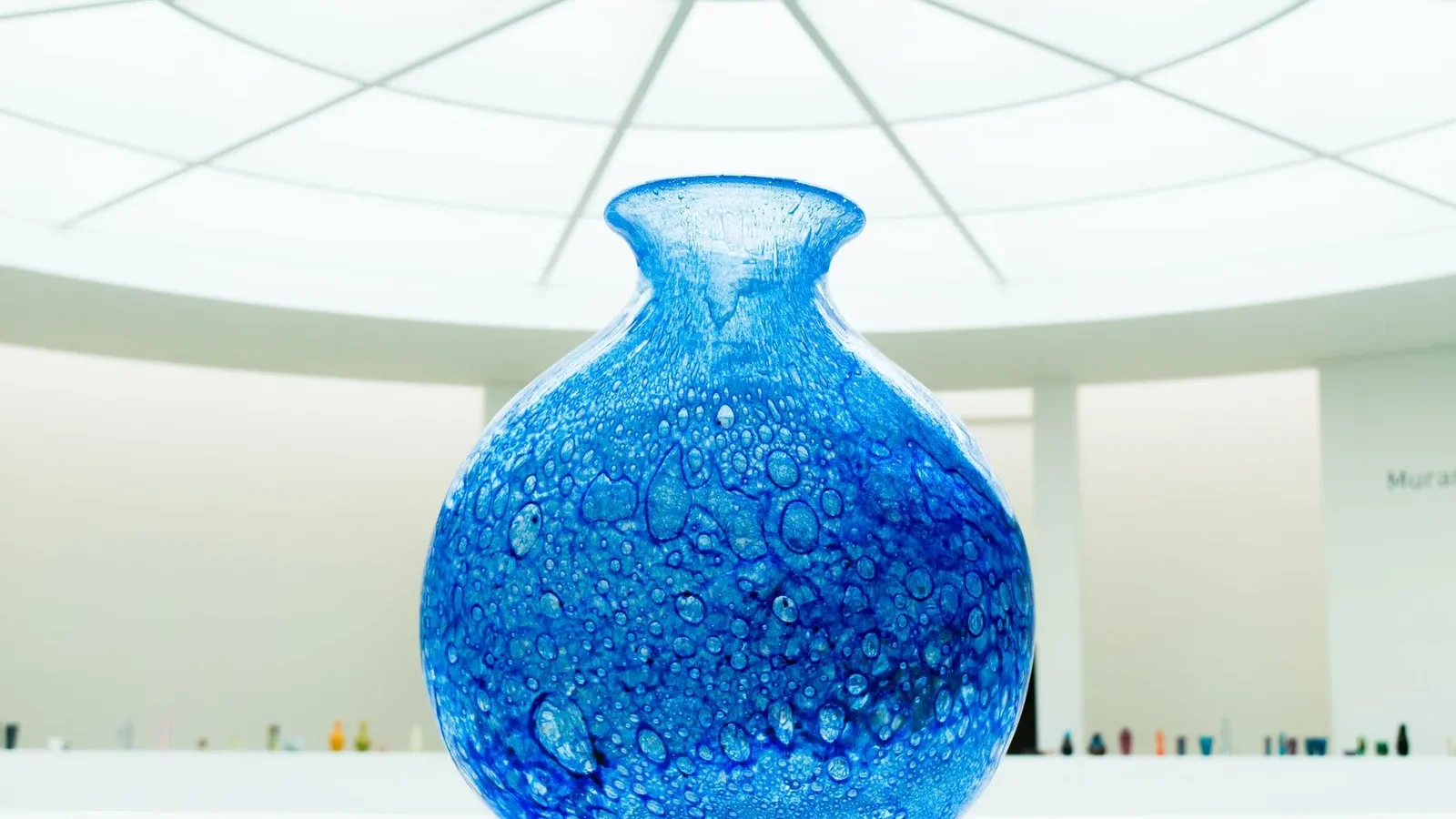 Vase en verre bleu soufflé exposé sous une lumière vive